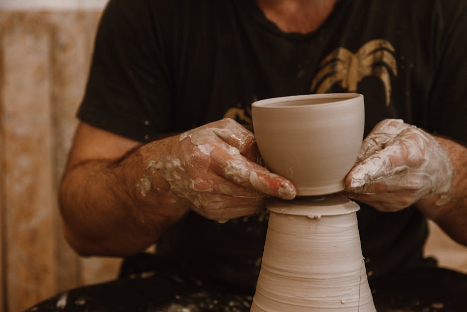 Hands expertly shaping a clay pot on a pottery wheel, showcasing the art of pottery.