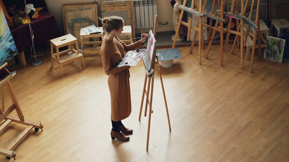 A young woman artist painting at an easel in a cozy art studio.