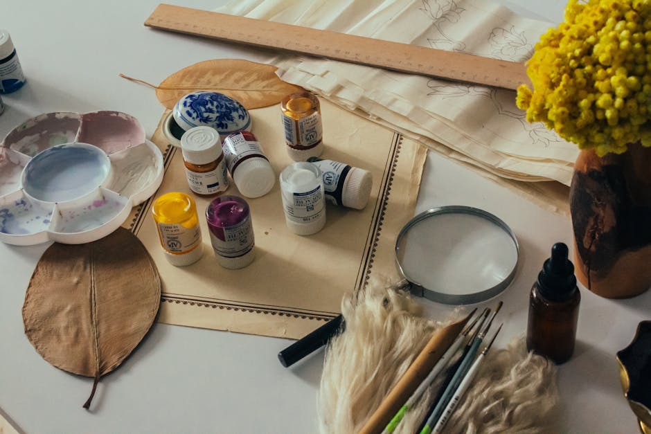 Creative art workspace featuring paints, brushes, and floral arrangement for vibrant projects.