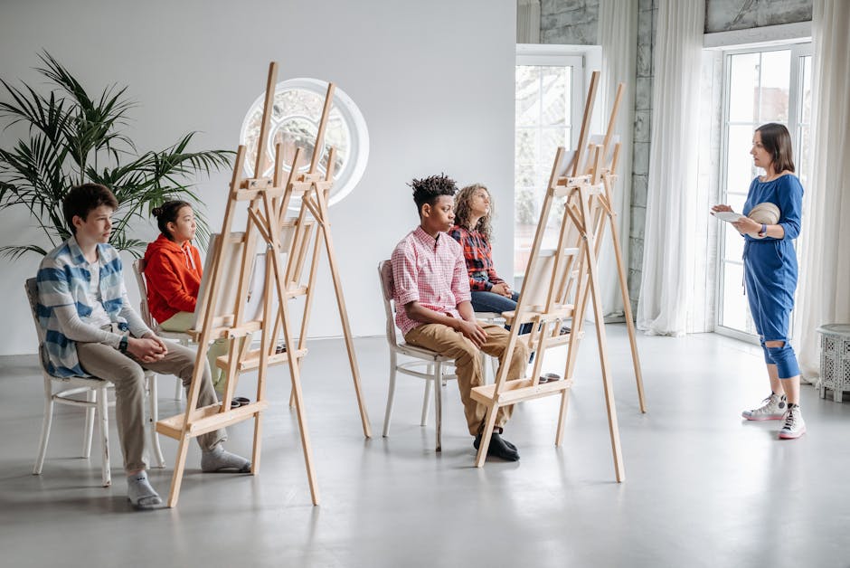 Students in an art class with easels, guided by a teacher in a bright studio setting.